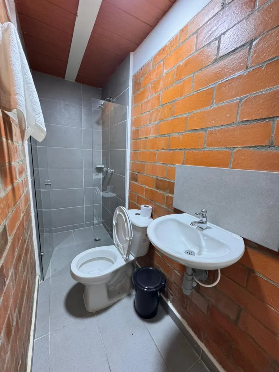 Baño privado con ducha de vidrio y pared de ladrillo